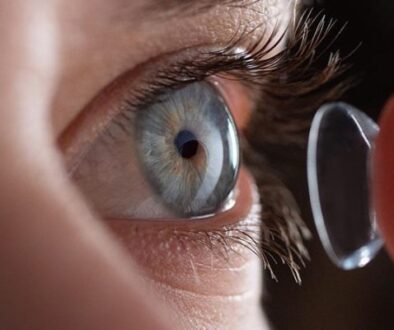 A close-up of an eye with a person inserting a contact lens, showcasing the procedure of placing contacts into the eye.
